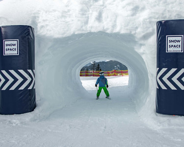 Child drives through snow tunnel at the Kidsrun in Flachau snow space Salzburg 