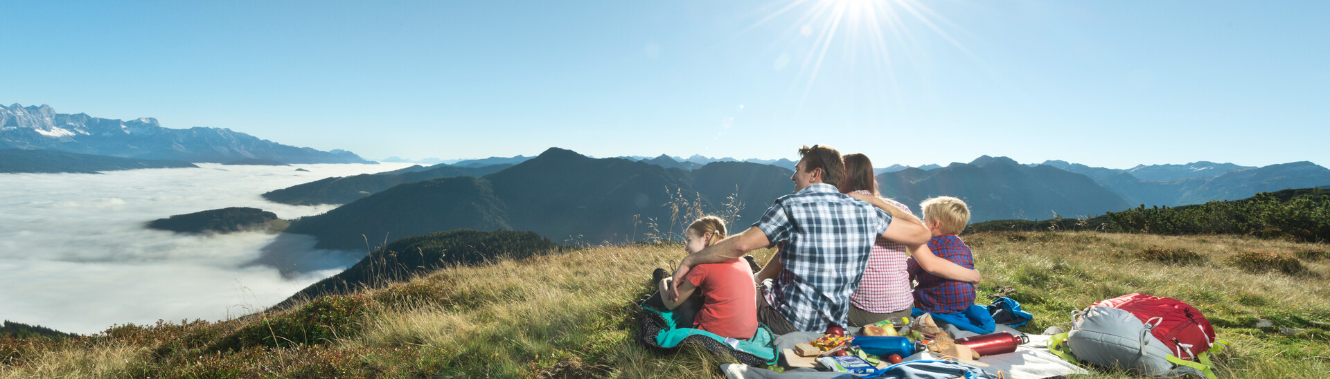 Familie genießt Ausblick in die Berge beim Picknicken | © Flachau Tourismus/Markus Berger