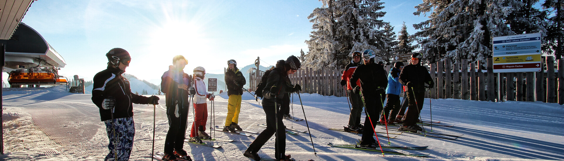 A group of skiers wait together at the mountain station Flachau on a sunny winter day