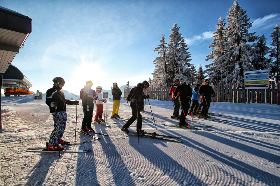 A group of skiers wait together at the mountain station Flachau on a sunny winter day