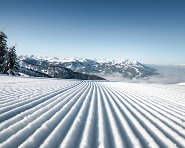 Freshly groomed ski slope with a view of the snow-covered winter landscape