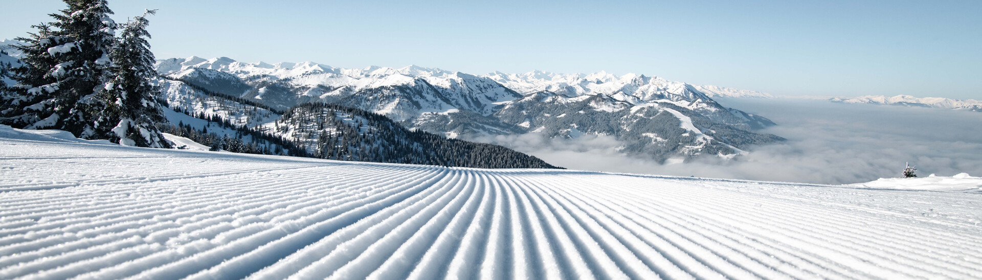 Frischpräparierte Skipiste mit Blick auf die verschneite Winterlandschaft