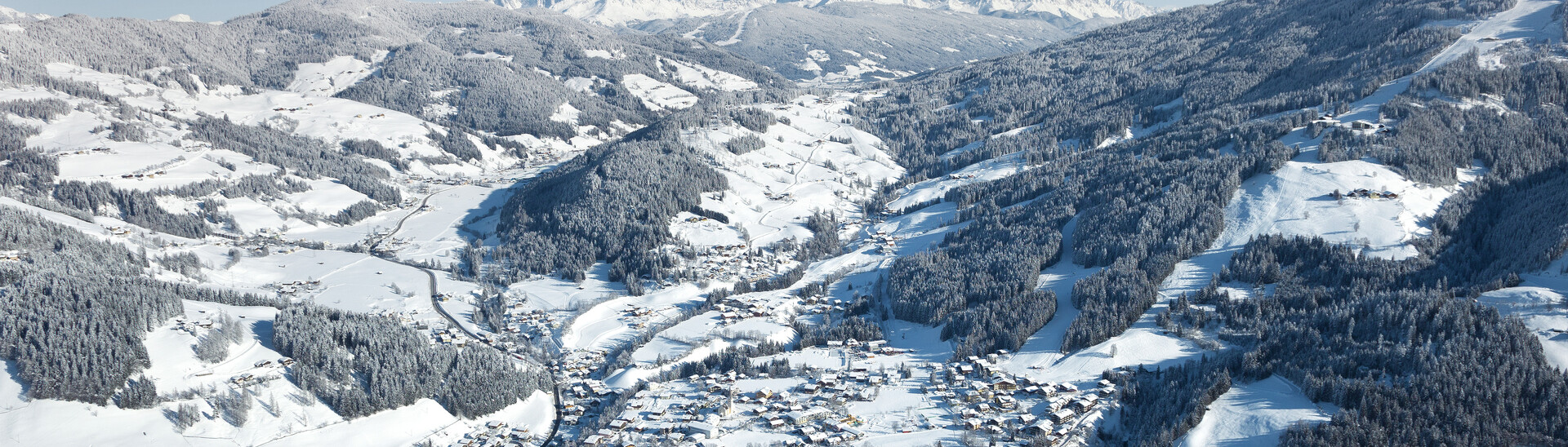 Flugaufnahme vom Ort Wagrain mit umliegender Winterlandschaft in Blickrichtung Flachau im Snow Space Salzburg | © Bergbahnen AG Wagrain