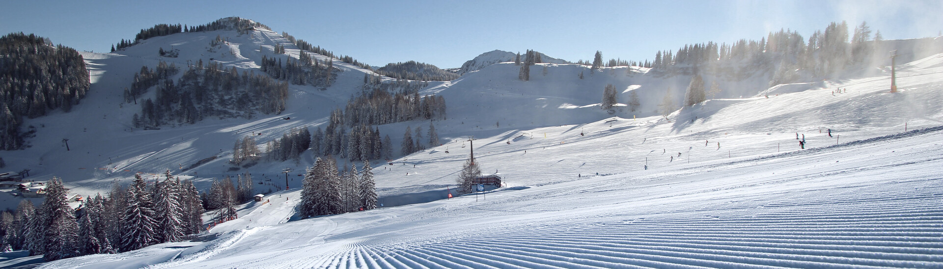 Freshly groomed slope in the sunshine of St. Johann-Alpendorf at Snow Space Salzburg ski resort, with a view of Sonntagskogel mountain | © Alpendorf Bergbahnen AG