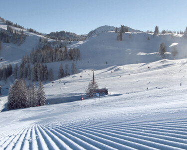 Freshly groomed slope in the sunshine of St. Johann-Alpendorf at Snow Space Salzburg ski resort, with a view of Sonntagskogel mountain | © Alpendorf Bergbahnen AG