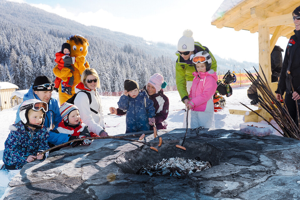 One of many family highlights at Snow Space Salzburg ski resort: the ski bunnies barbecue party at WAGRAINi’s Winter World, every Thursday at 14:00! | © Bergbahnen AG Wagrain Children and adults cooking sausages over a fire during the ski bunnies barbecue party at WAGRAINi’s Winter World at Snow Space Salzburg | © Bergbahnen AG Wagrain