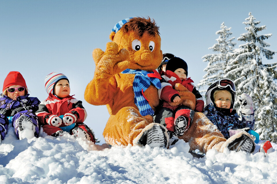 Children enjoy the skiing holiday in a playful manner with the mascot of the ski area of Wagrain