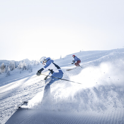 Zwei Skifahrer ziehen ihre Schwünge über die perfekt präparierten Pisten im Skigebiet Snow Space Salzburg | © Ski amadé