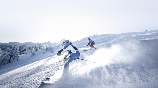 Zwei Skifahrer ziehen ihre Schwünge über die perfekt präparierten Pisten im Skigebiet Snow Space Salzburg | © Ski amadé