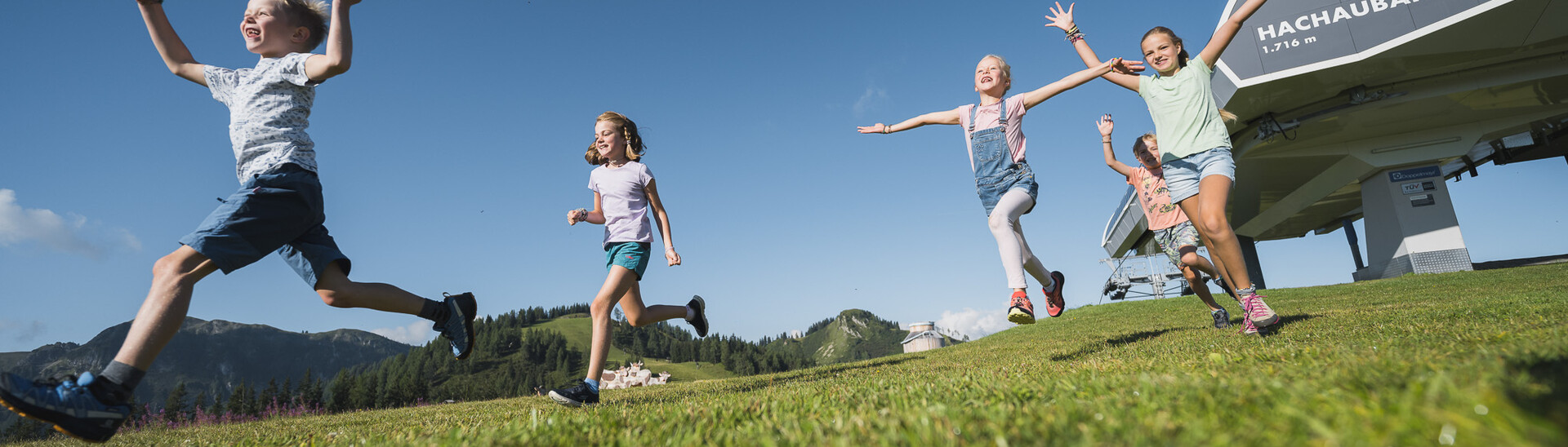 Happy children playing on the meadows near the mountain station 