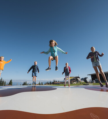 Children jumping on outdoor trampoline in Snow Space